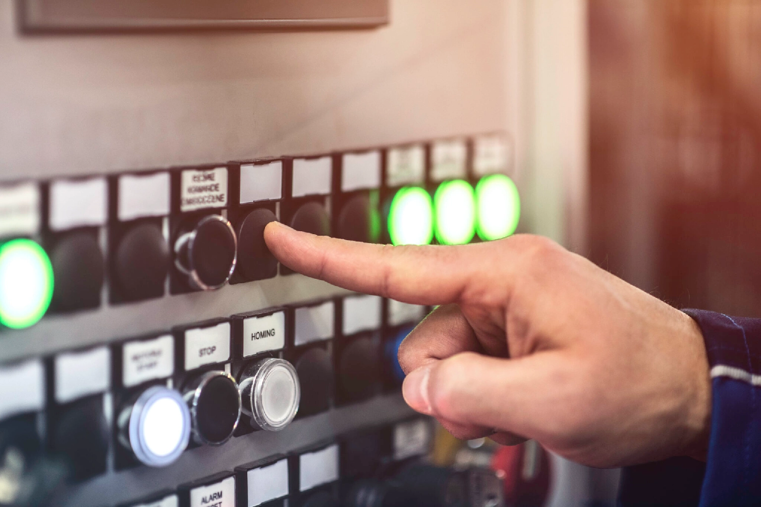A hand pressing a button on a control panel with illuminated indicators.